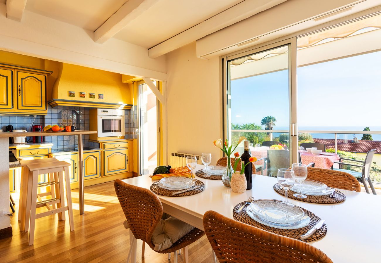 Sunny kitchen with dining area, opening onto a terrace with a sea view.