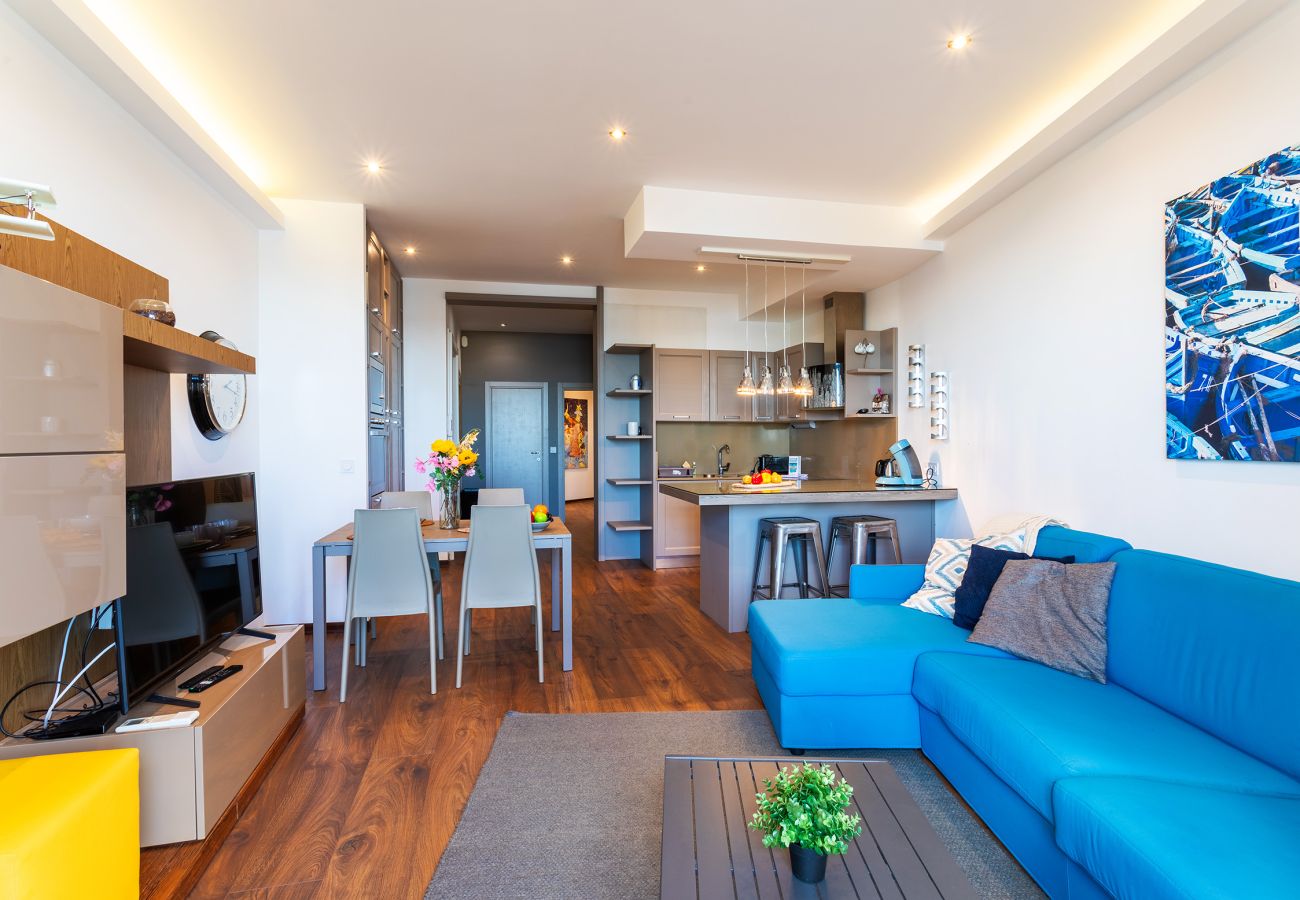 Salon moderne et coloré, cuisine ouverte équipée. Espace chaleureux et convivial pour se détendre.