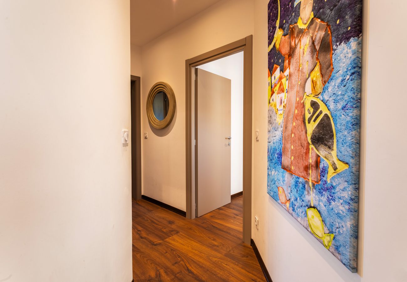 Couloir décoré avec un tableau coloré et un miroir design